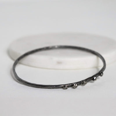 Textured sterling silver nugget bangle lying flat, showing its irregular hammered surface and raised fused silver details.