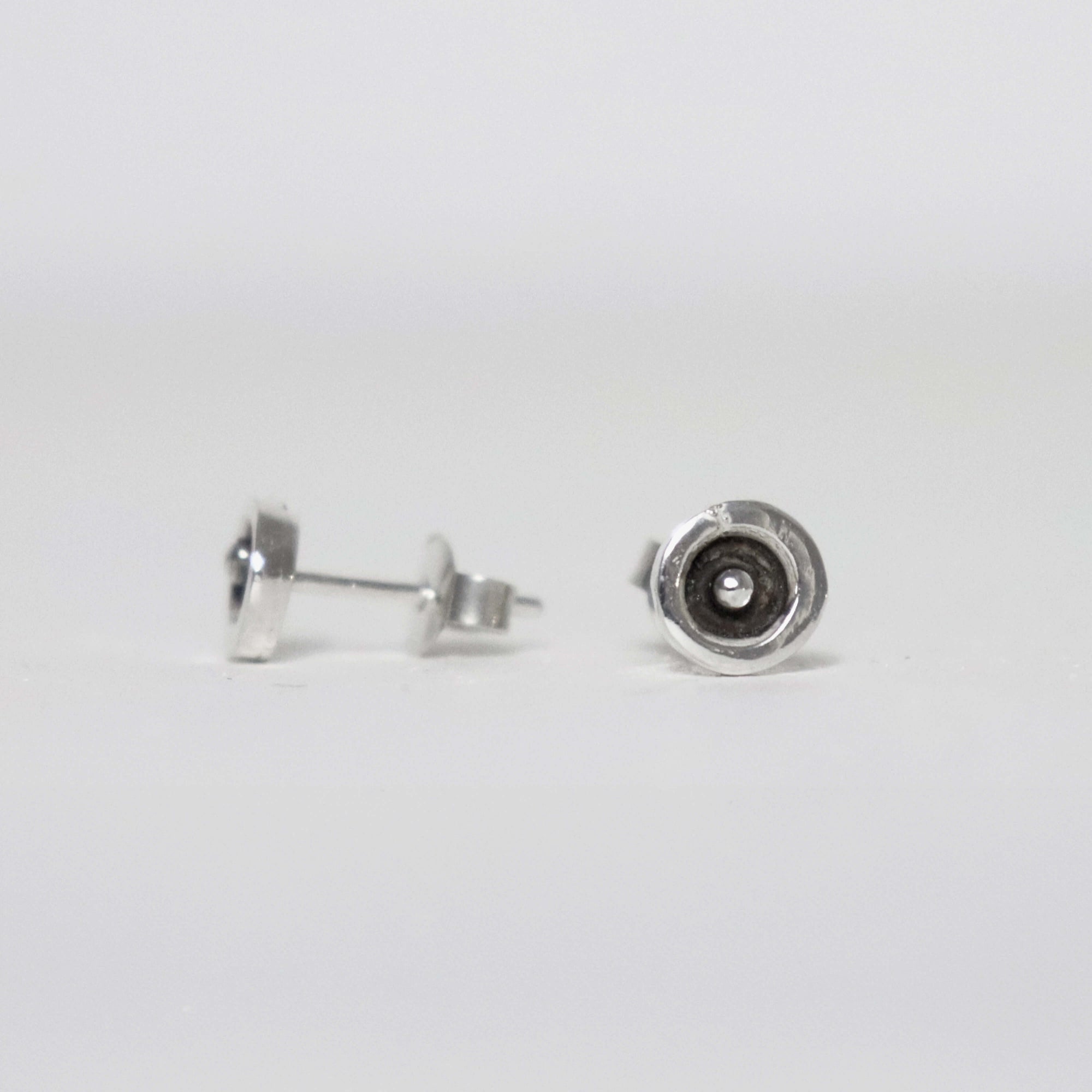 Small 7 mm sterling silver stud earrings featuring a raised silver dot inside a polished circular rim with a blackened centre