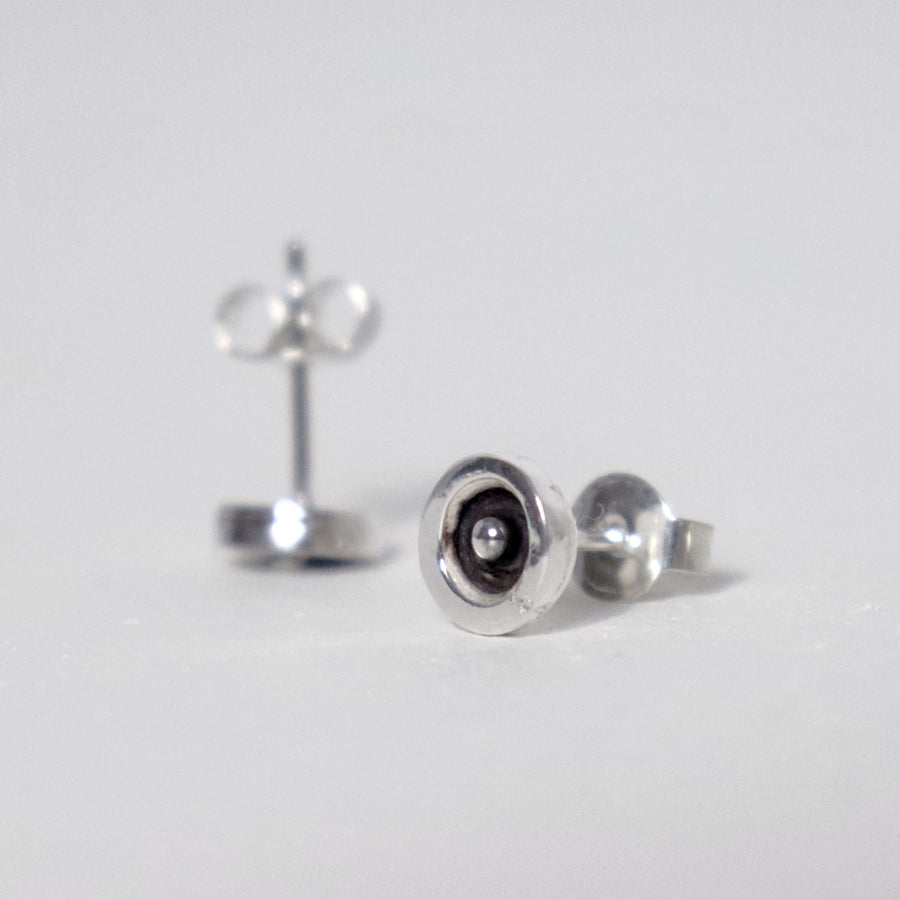 Handmade sterling silver circle and dot stud earrings with dark oxidized centres, polished silver dots and butterfly backs.