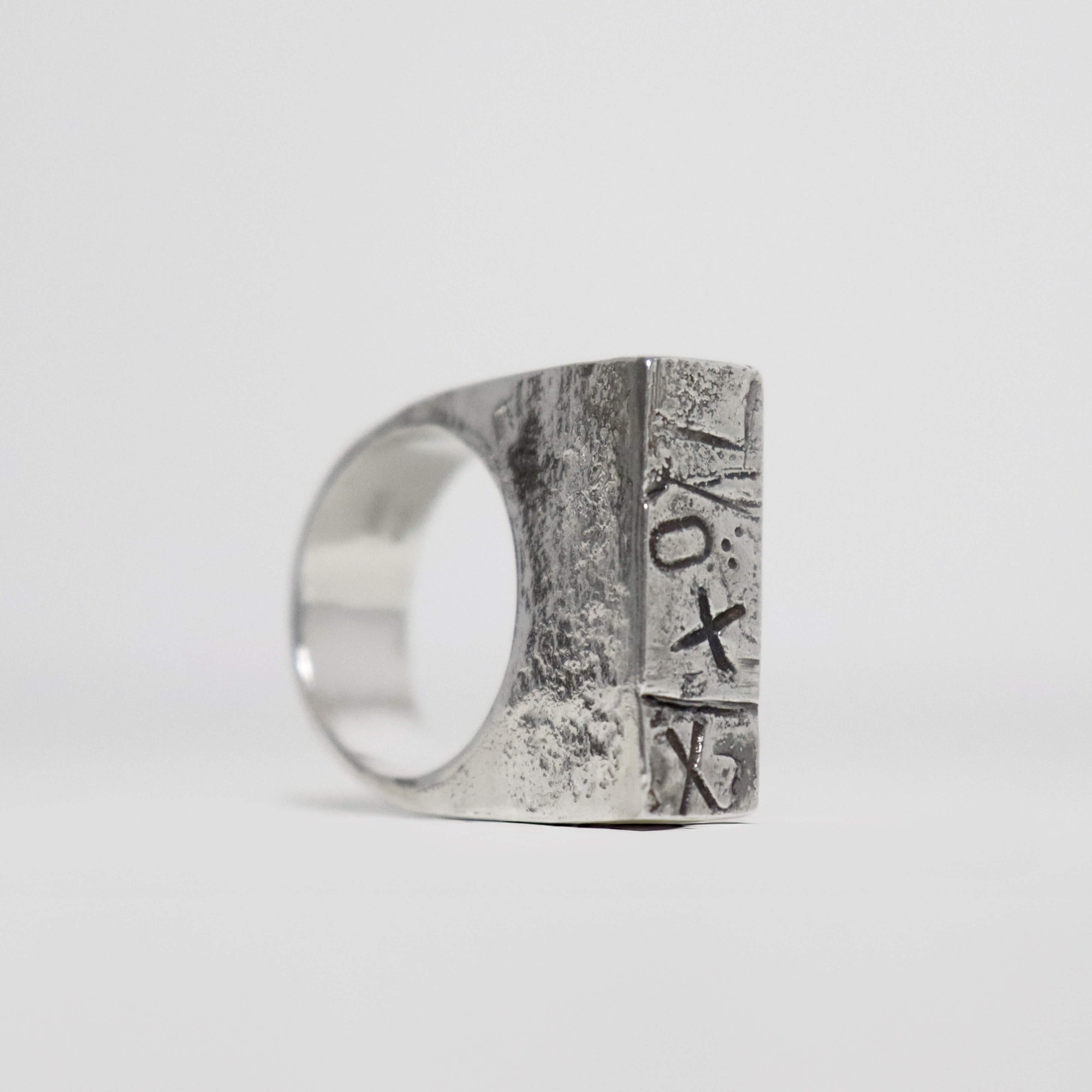 Chunky sterling silver XXO signet ring with geometric rectangular top, abstract stamped symbols and textured oxidised silver.