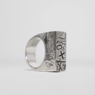 Chunky sterling silver XXO signet ring with geometric rectangular top, abstract stamped symbols and textured oxidised silver.
