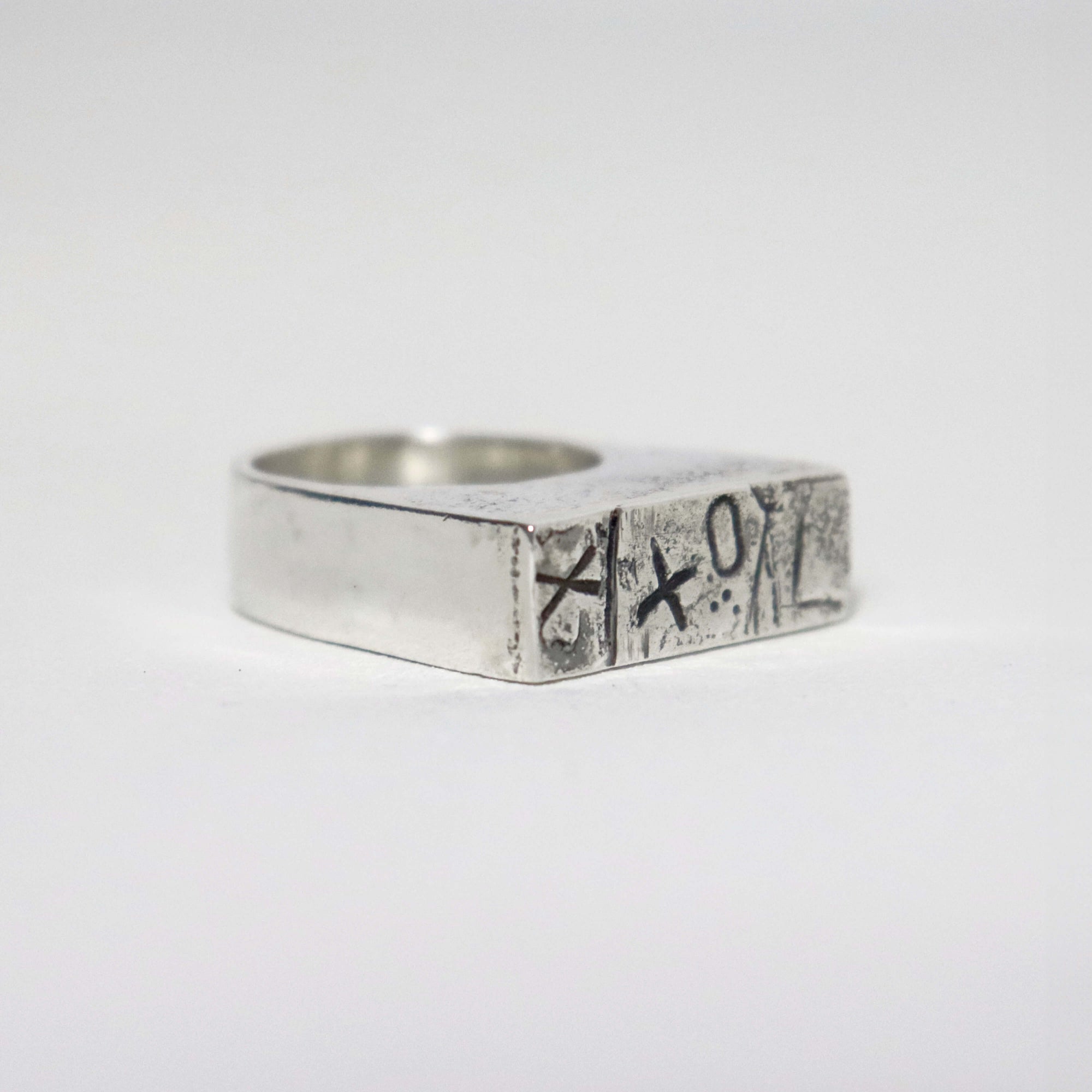 One of a kind sterling silver signet ring with hand-stamped XXO pattern, oxidised details and silver sawdust texture.