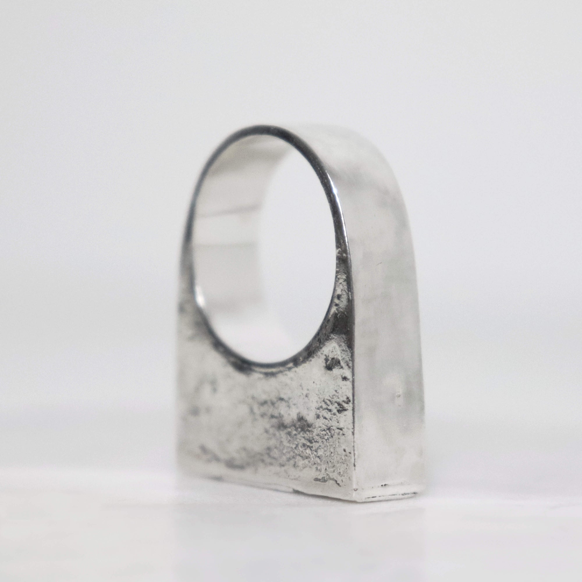 Handcrafted chunky silver signet ring with wide polished band, textured sterling silver surface and geometric sculptural shape.