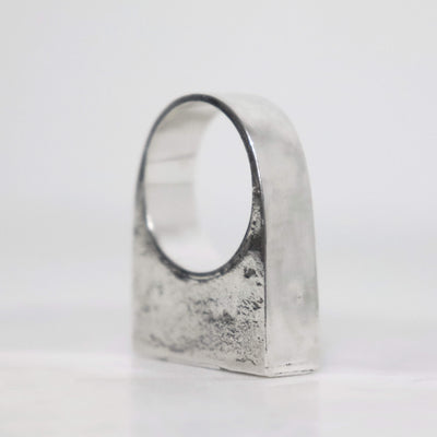 Handcrafted chunky silver signet ring with wide polished band, textured sterling silver surface and geometric sculptural shape.