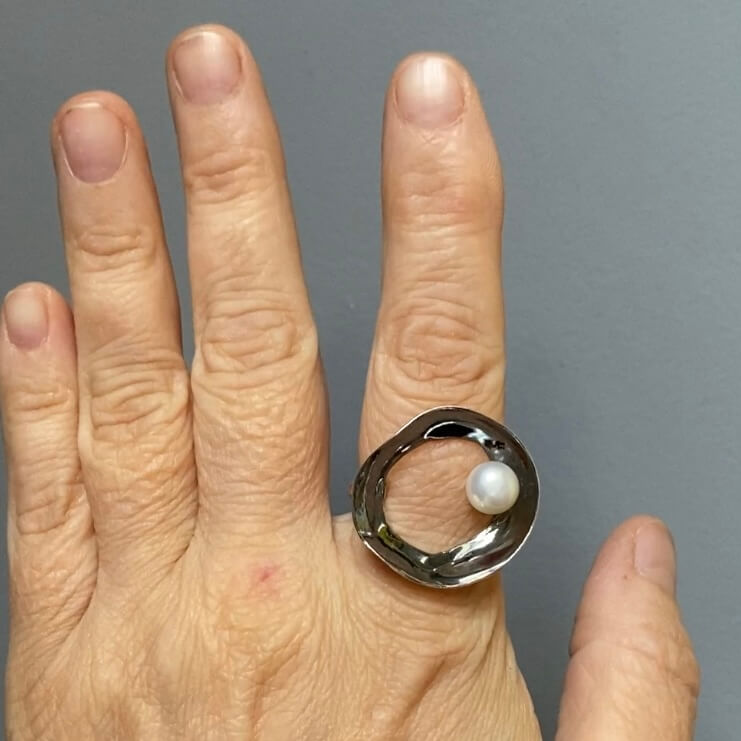 ladies hand showing a black oxidized silver retro sixties ring with white peal by roff jewellery
