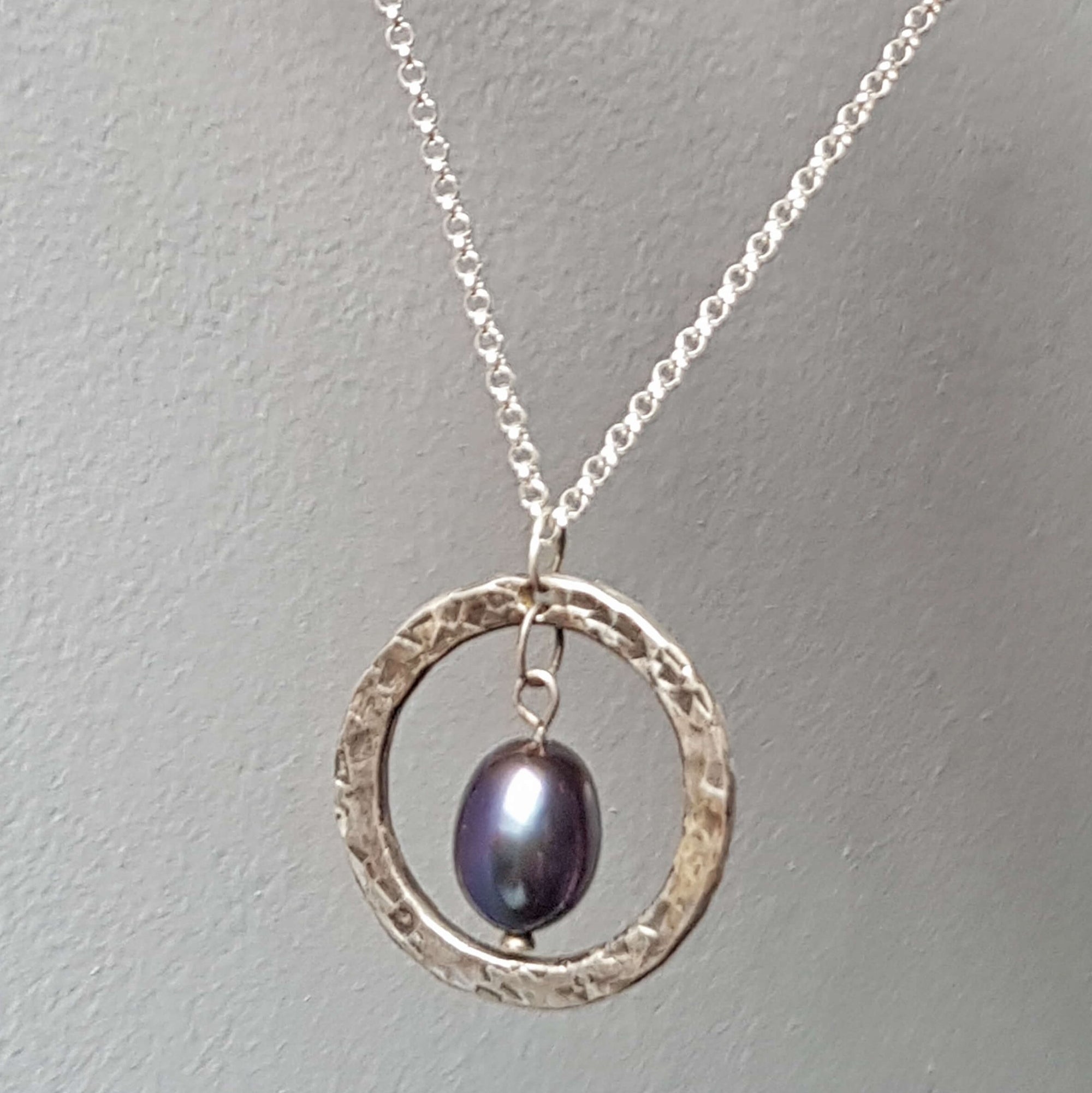 Hammered and oxidized circular silver pendant with blue black pearl, handmade by roff jewellery