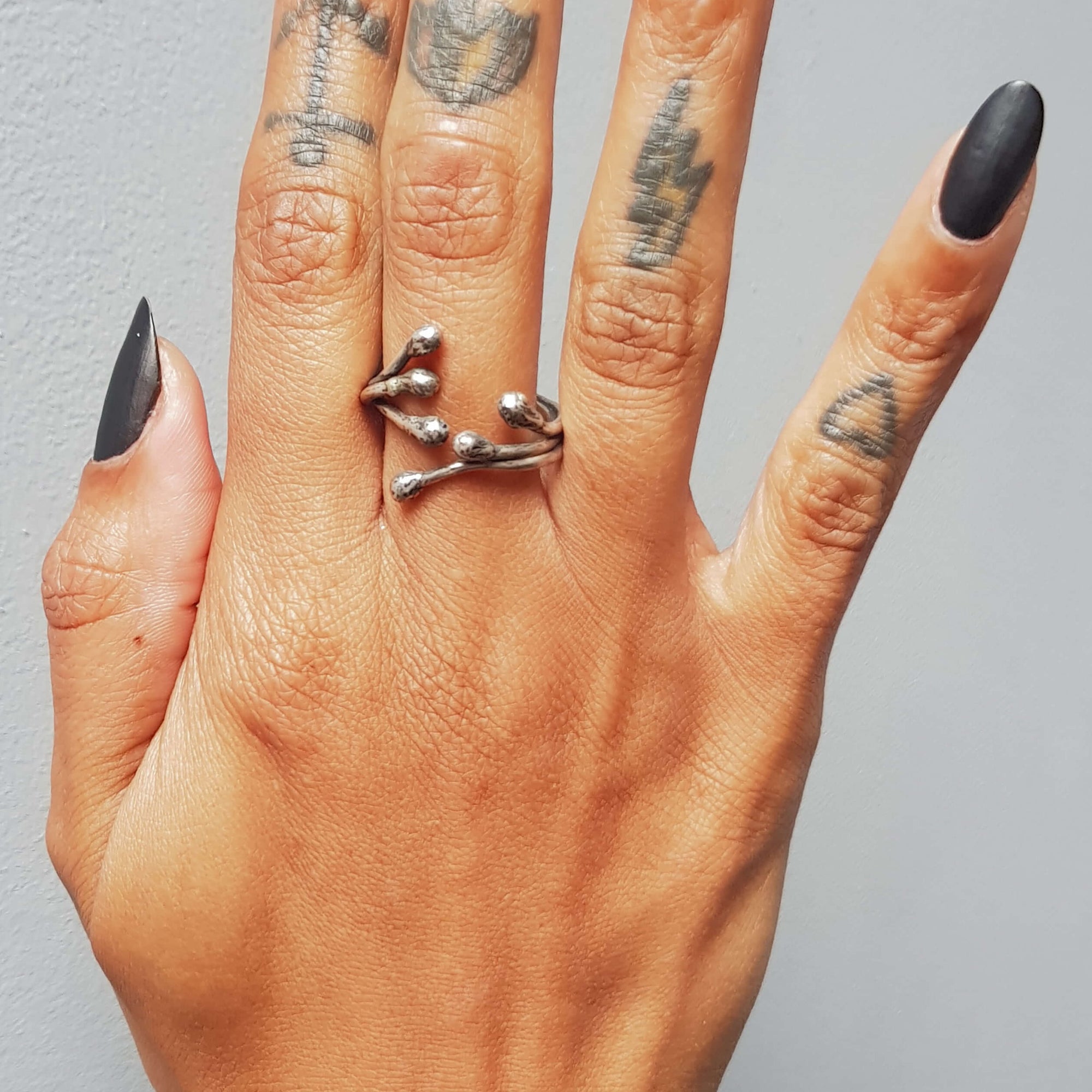 womens hand wearing an oxidized silver wire ring, open in the front, handforged and hammered by roff